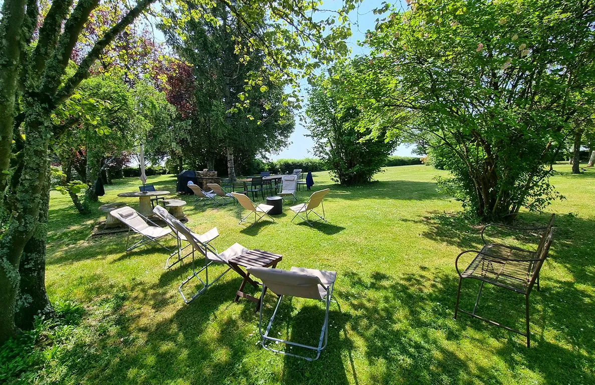 Coin détente ombragé sous les arbres avec chaises longues et table de jardin