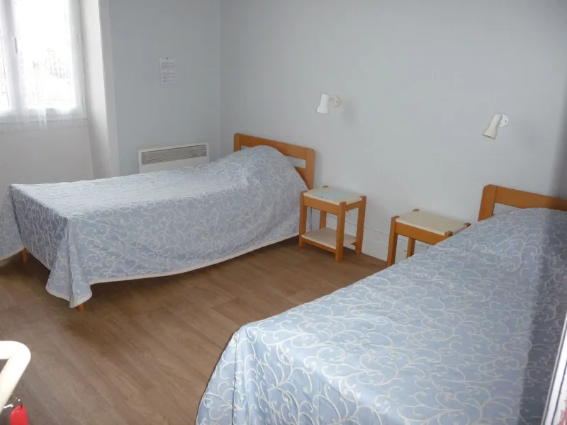 Chambre avec deux lits simples et couvre-lits assortis
