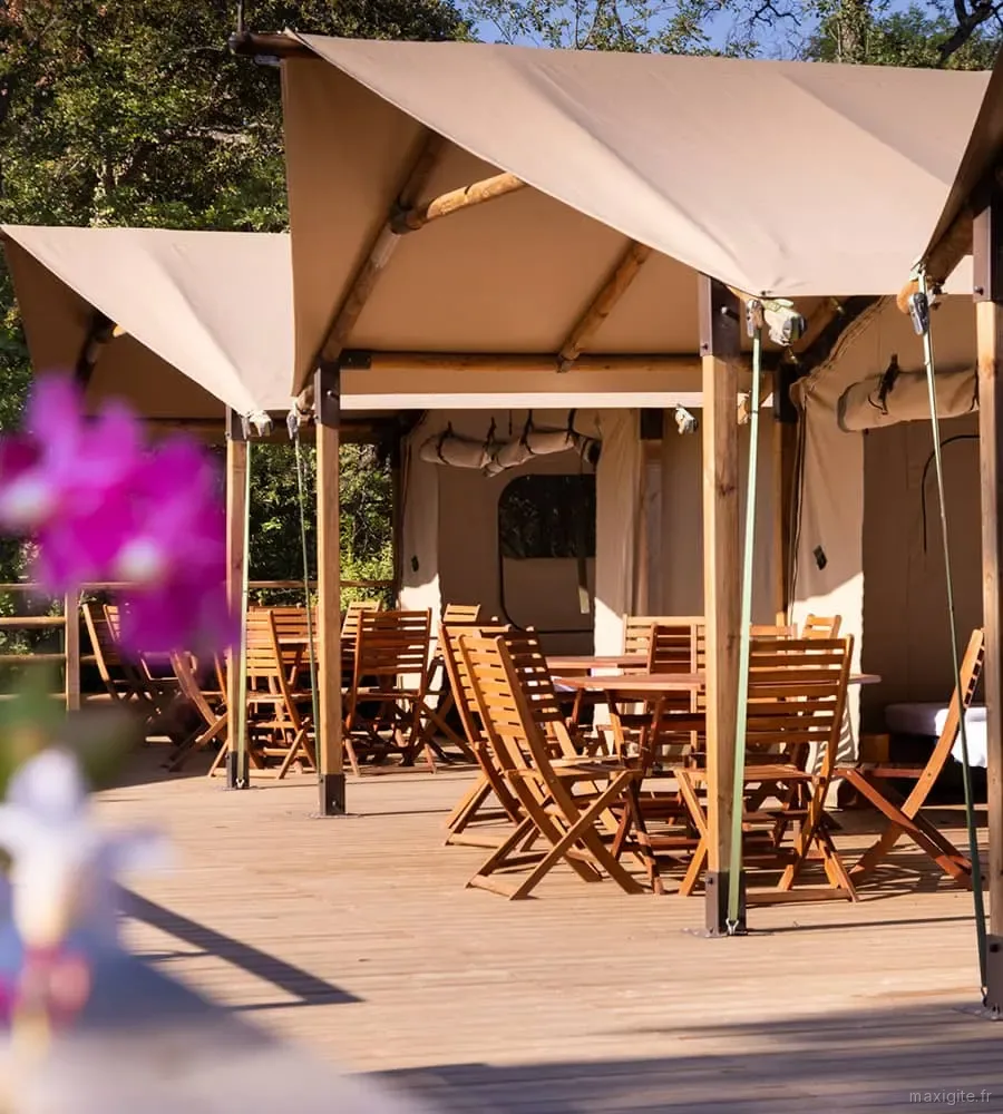 Terrasse en bois d'un lodge avec tables et chaises pour les temps de vie collective