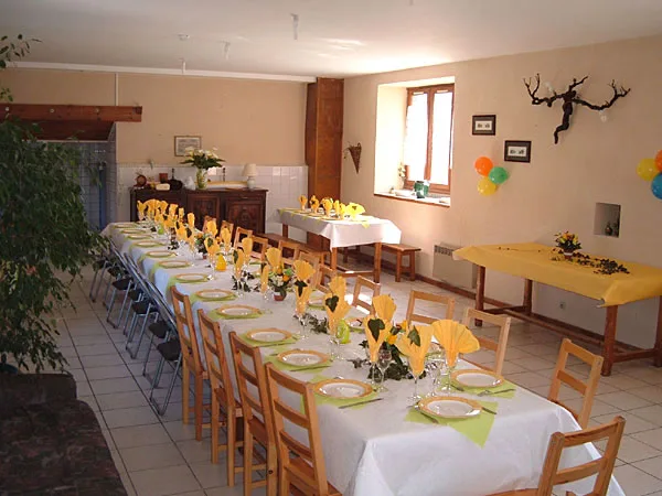 Grande salle commune dressée avec longues tables pour un repas de groupe convivial