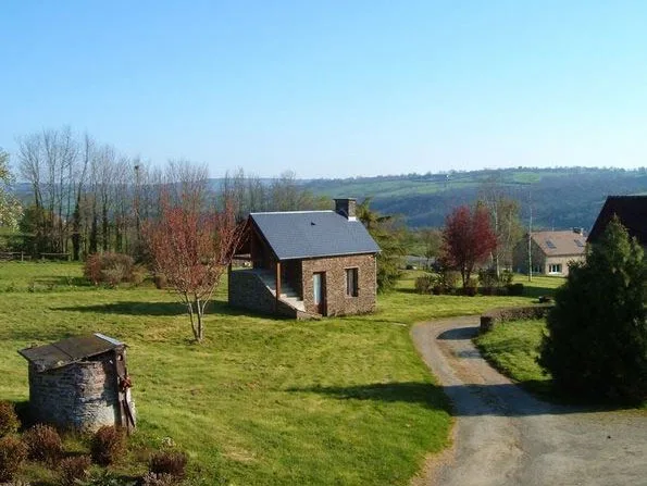 Petite maison en pierre isolée dans la prairie avec vue dégagée sur les collines du bocage