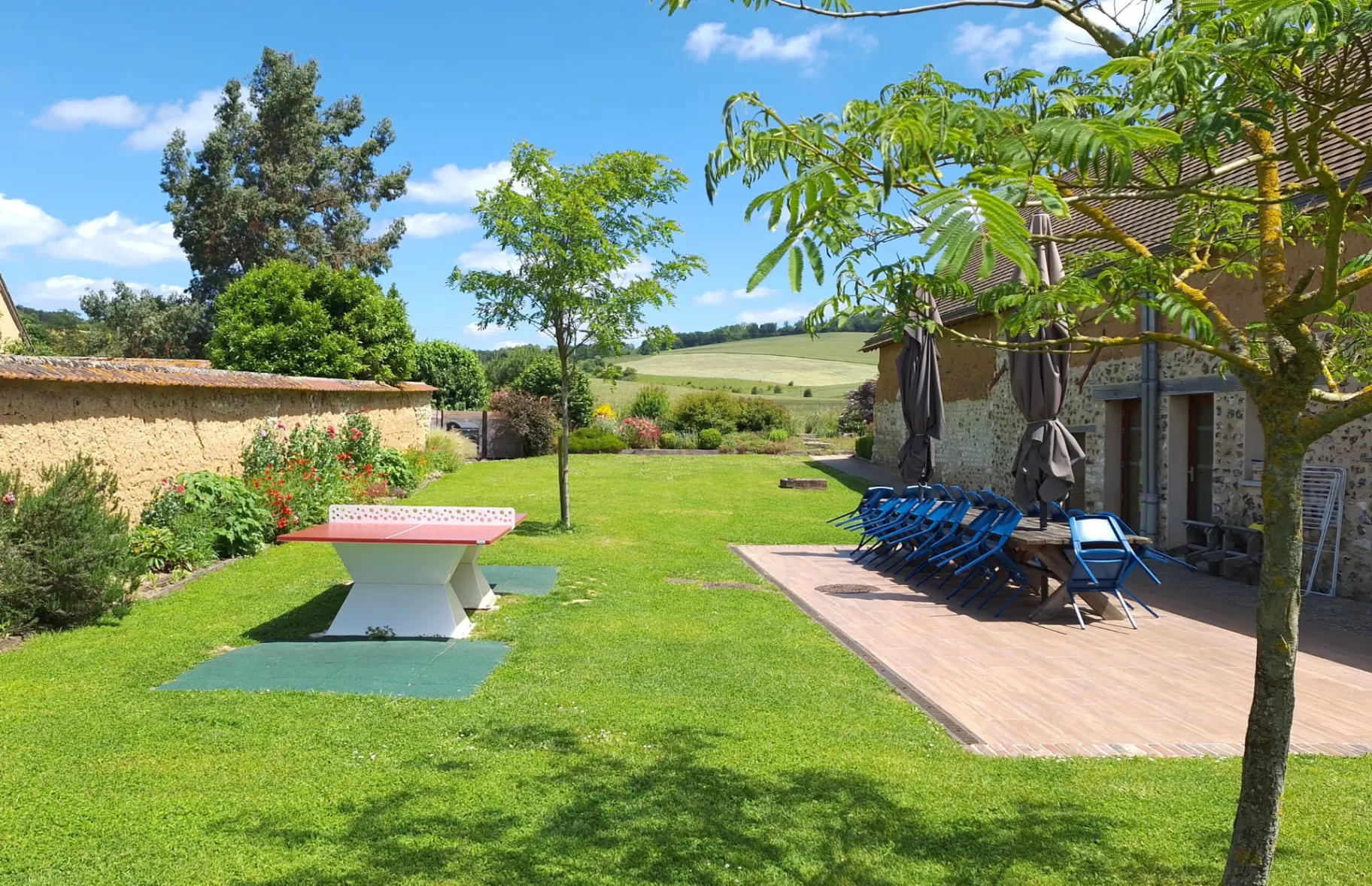 Gîte de groupe Champ de l'être à La Croix-Saint-Leufroy — Terrasse en bois du gîte avec grande table conviviale et vue sur la campagne normande, capacité 20 personnes