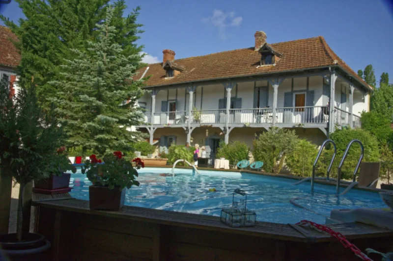 Vue de la maison de maître depuis la piscine entourée d'un jardin fleuri
