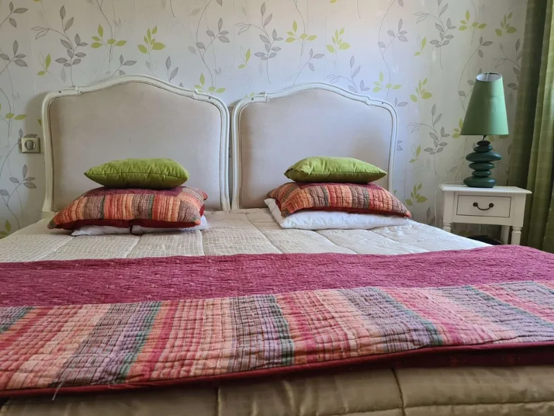 Chambre double avec têtes de lit capitonnées et linge de lit fleuri