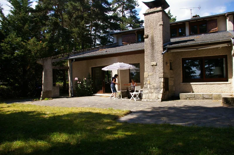 Façade en pierre de la maison d'architecte avec terrasse ombragée et cheminée en granit