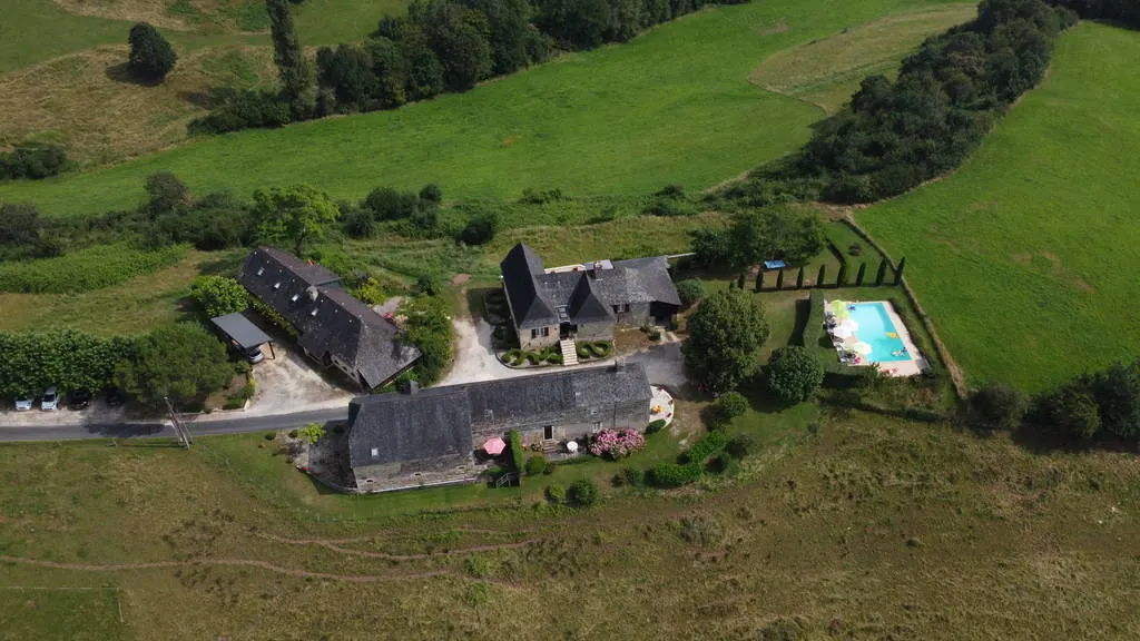 Gîte de groupe Domaine Leyvinie à Perpezac-le-Blanc — Vue aérienne du domaine avec ses gîtes en pierre et sa piscine entourée de prairies, capacité 31 personnes
