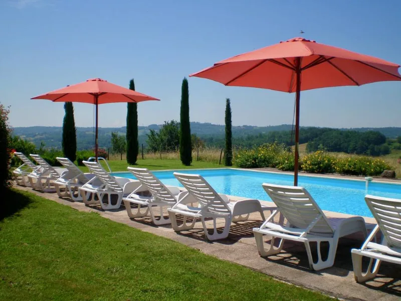 Piscine avec transats et parasols, vue dégagée sur la campagne corrézienne