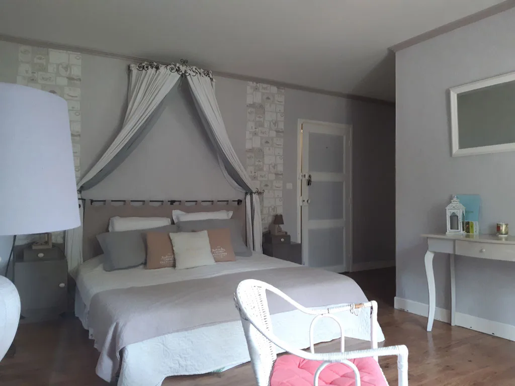 Chambre lumineuse avec literie double, murs clairs et ambiance champêtre