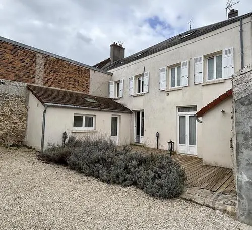 Gîte de groupe Gîte du Postier à Boissy-sous-Saint-Yon — Façade enduite de la maison de ville avec volets blancs et terrasse en bois à l'arrière, capacité 15 personnes