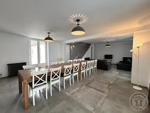 Grande salle à manger avec longue table en bois et chaises blanches pour recevoir le groupe