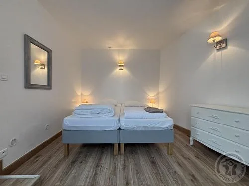 Chambre double avec deux lits jumeaux, appliques murales et commode blanche