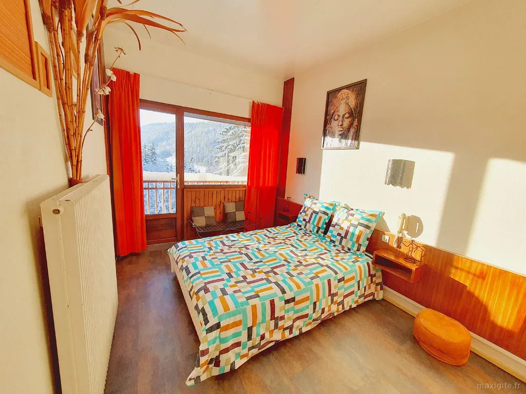Chambre aux tons rouges avec literie fleurie et mobilier en bois