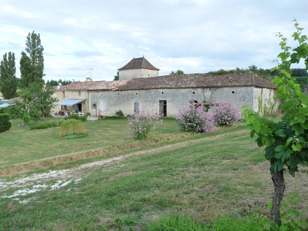 Gîte de groupe Les Gîtes du Garry à Thénac — Façade en pierre du gîte du Garry entourée d'un grand jardin arboré et fleuri, capacité 20 personnes