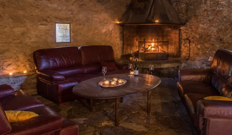 Salon en pierre avec cheminée et canapés en cuir pour les soirées d'hiver