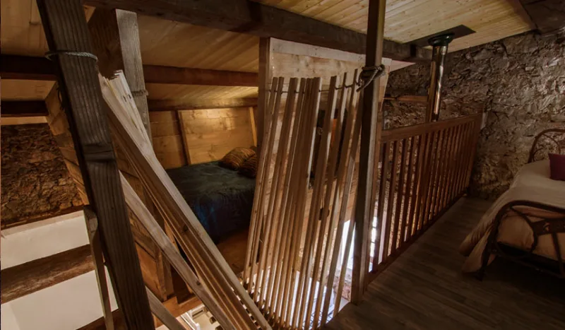 Mezzanine en bois avec balustrade rustique surplombant l'espace de couchage