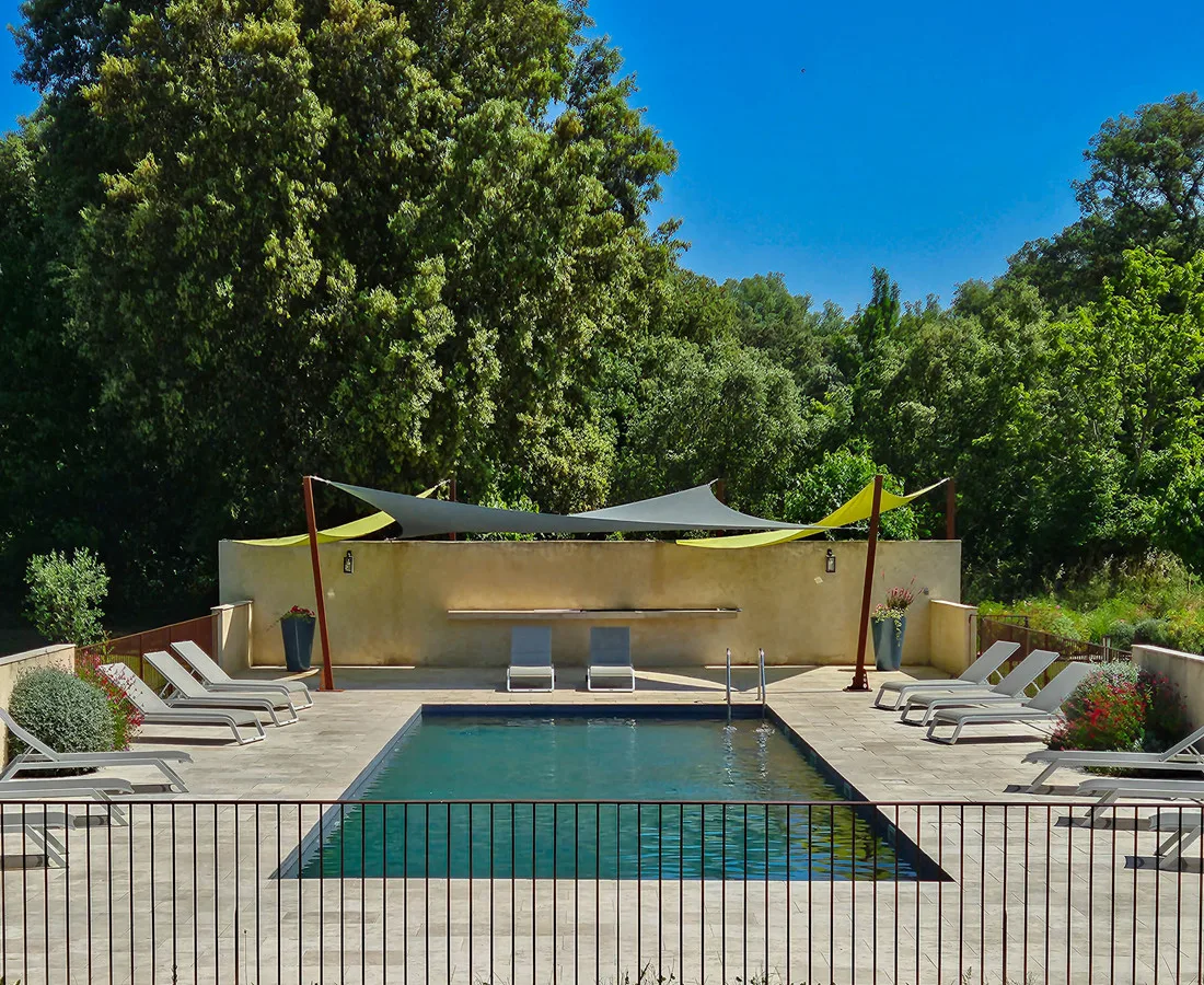 Piscine du domaine avec plage engazonnée et transats au soleil