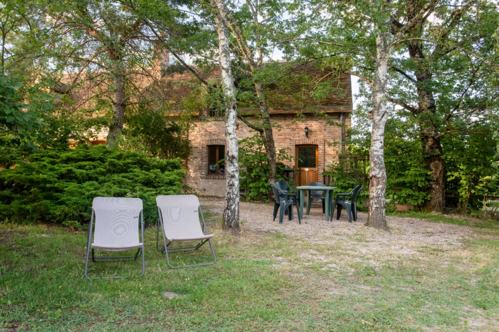 Jardin extérieur avec chaises longues devant le gîte en brique dans un cadre boisé