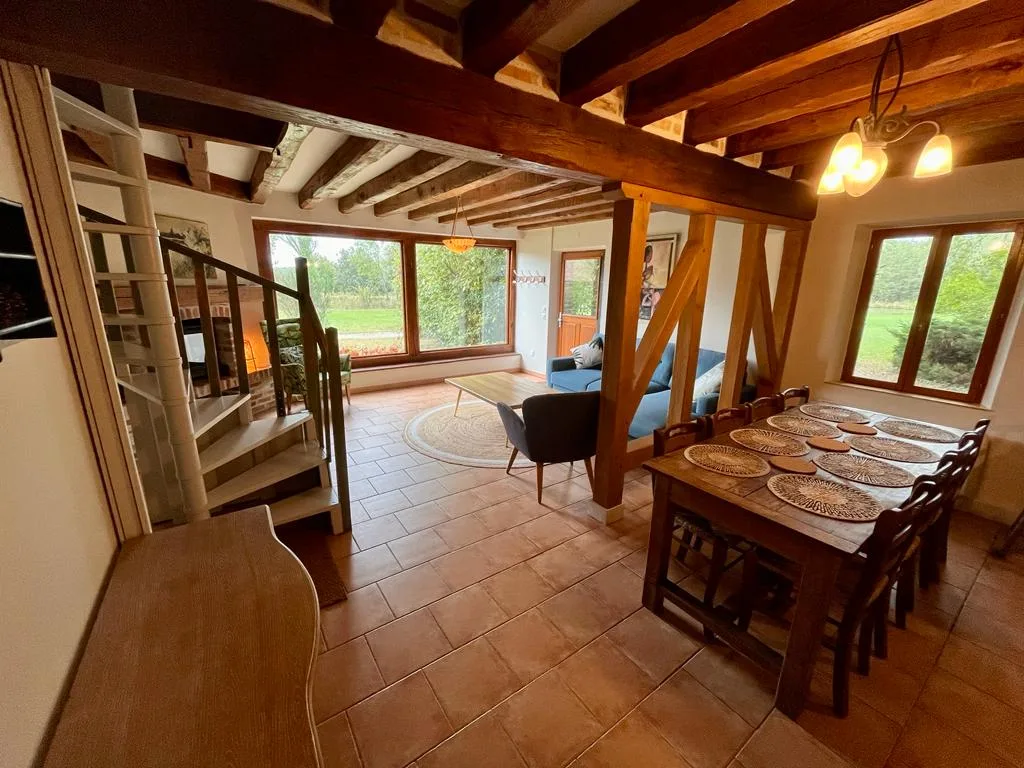 Séjour avec poutres apparentes en chêne, grande table à manger et vue sur le parc