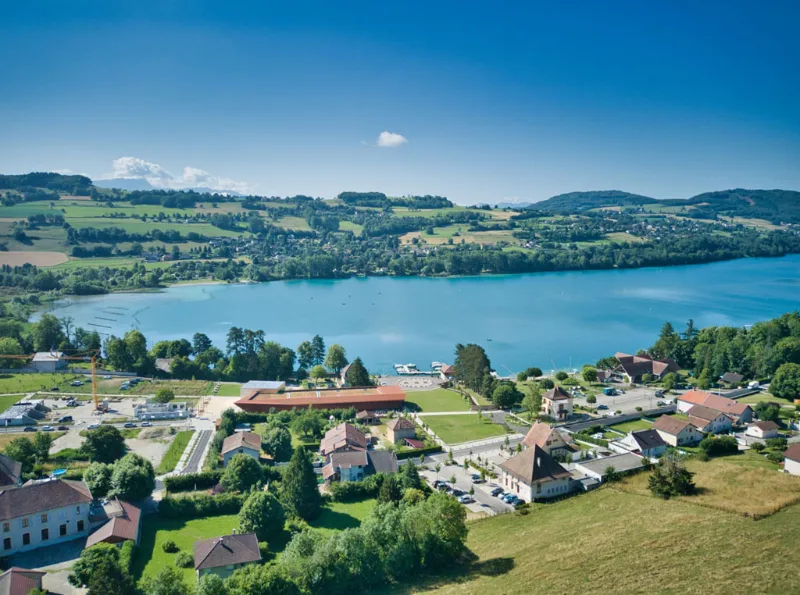 Vue aérienne du lac de Paladru avec le village et le Centre Bellevue en contrebas, entouré de verdure