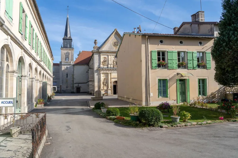 Cour principale du Centre d'Accueil de Benoîte-Vaux avec bâtiments historiques, église et jardin verdoyant