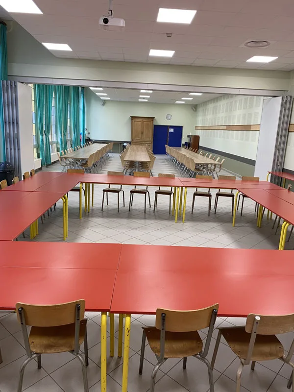 Grande salle de réunion avec tables disposées en U, vidéoprojecteur et rideaux verts