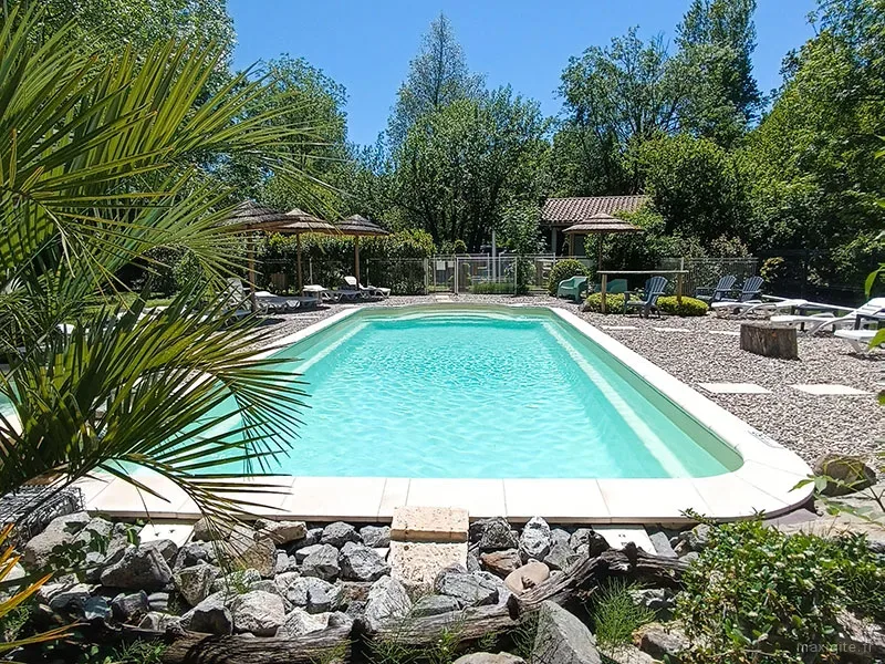 Espace piscine avec transats et parasols entourée de végétation méditerranéenne