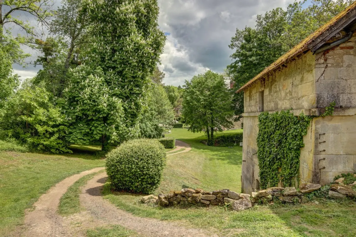 Parc arboré du Domaine des Forges de la Vache avec arbres centenaires et ruisseau traversant la propriété