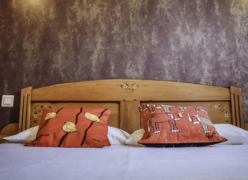 Chambre avec lit double et tête de lit en bois sculpté aux coussins orangés brodés