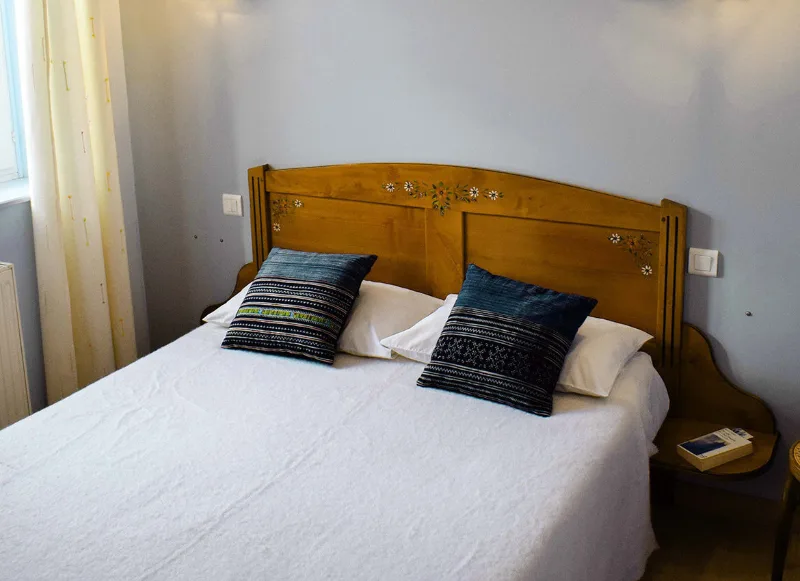 Chambre avec lit double, tête de lit en bois et coussins bleus coordonnés