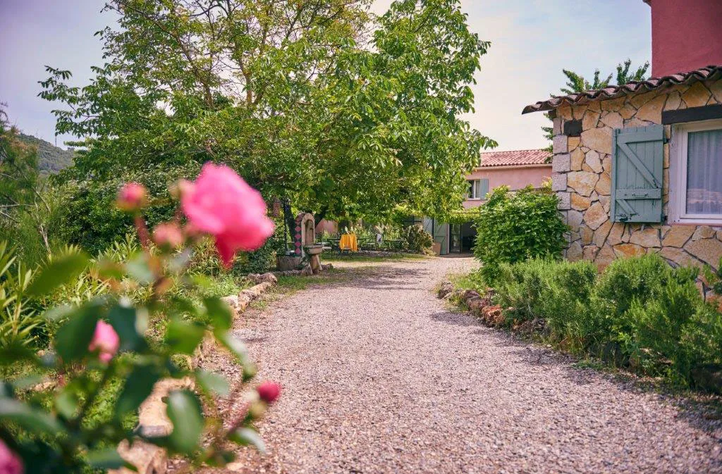Jardin fleuri du domaine avec rosiers en fleur et bastide provençale en arrière-plan