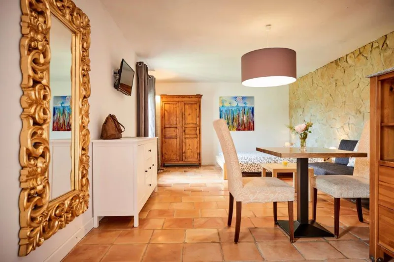Salle à manger d'un gîte avec table et chaises blanches, miroir doré et luminaire