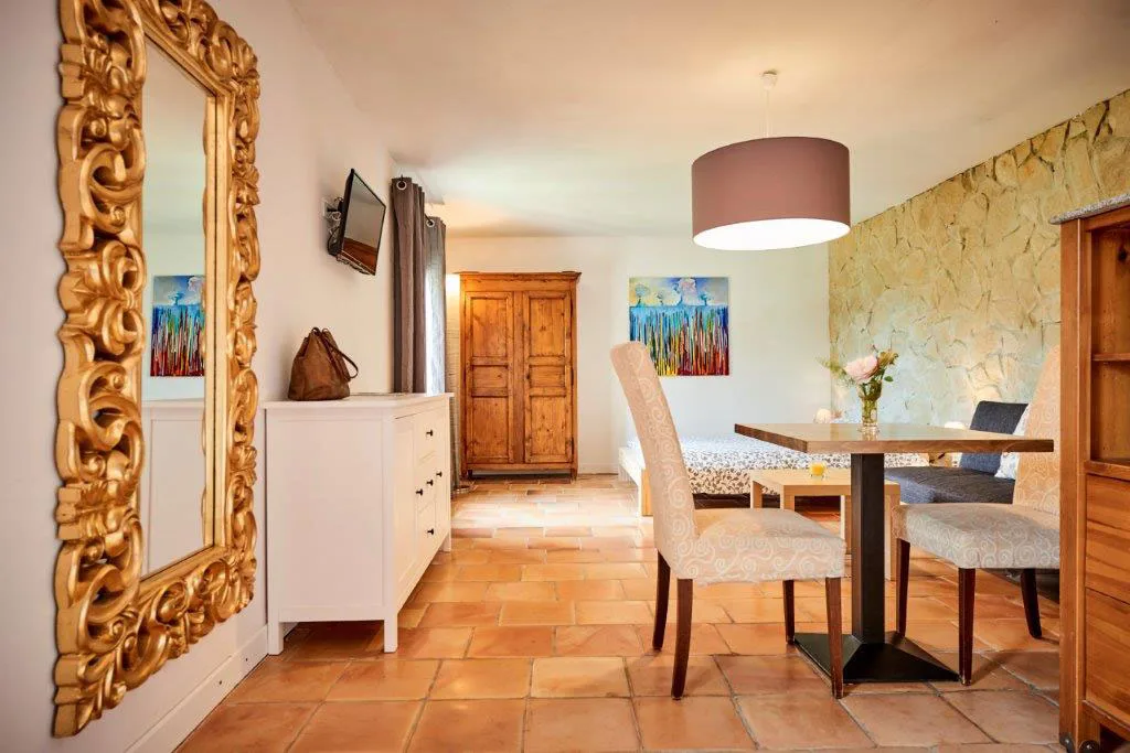 Salle à manger d'un gîte avec table et chaises blanches, miroir doré et luminaire
