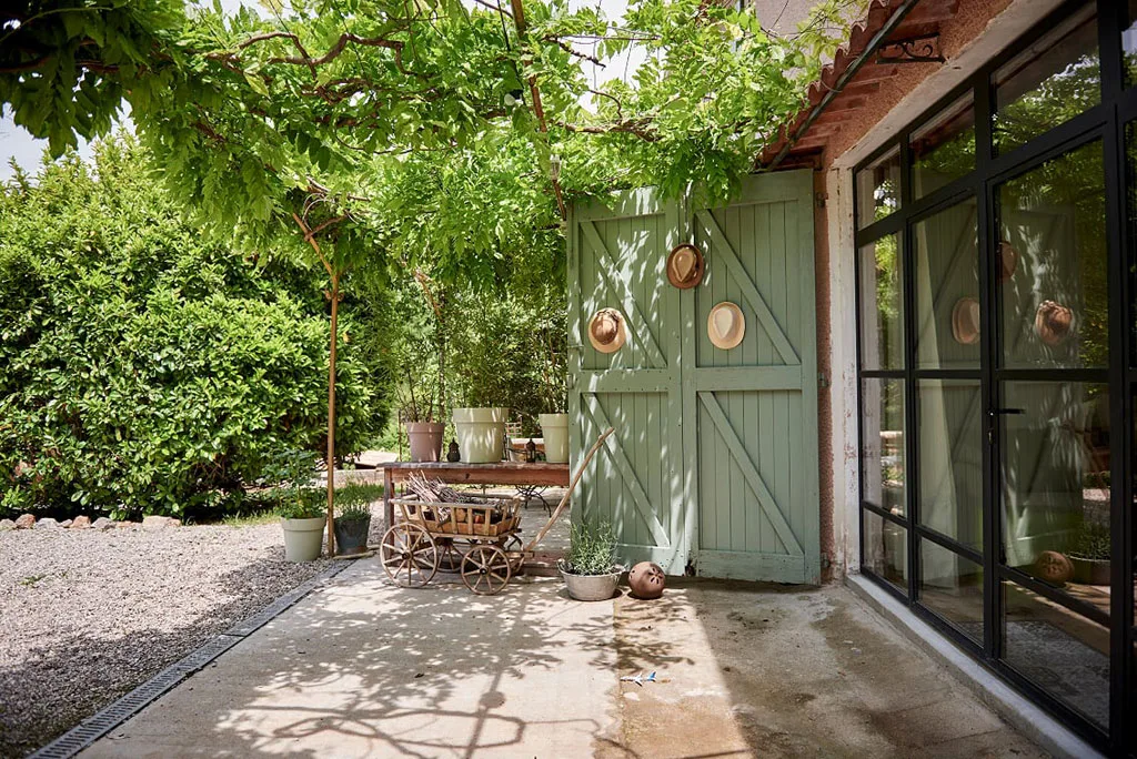 Terrasse privative d'un gîte avec porte verte, pergola ombragée et salon de jardin
