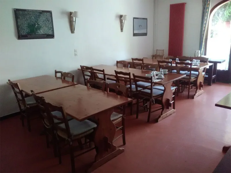 Réfectoire du centre avec tables et chaises alignées, carrelage rouge et lumière naturelle