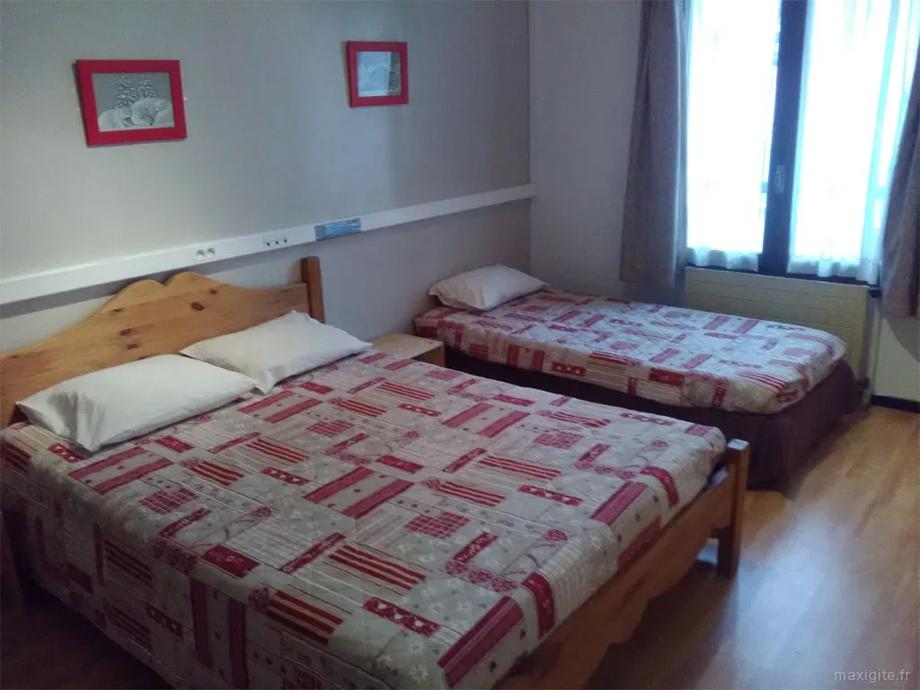 Chambre twin avec deux lits en bois et couettes à motifs rouge et blanc
