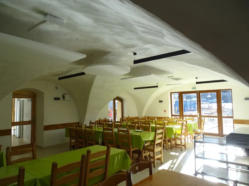 Salle de restauration lumineuse avec tables à nappes vertes et plafond voûté