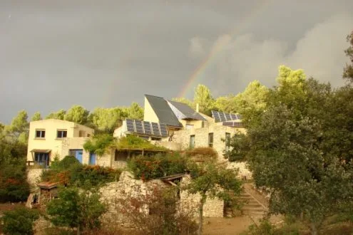 Vue extérieure de l'écogîte sous un arc-en-ciel avec paysage boisé de Provence