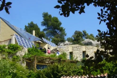 Vue de l'écogîte avec panneaux solaires en toiture et façade en matériaux naturels