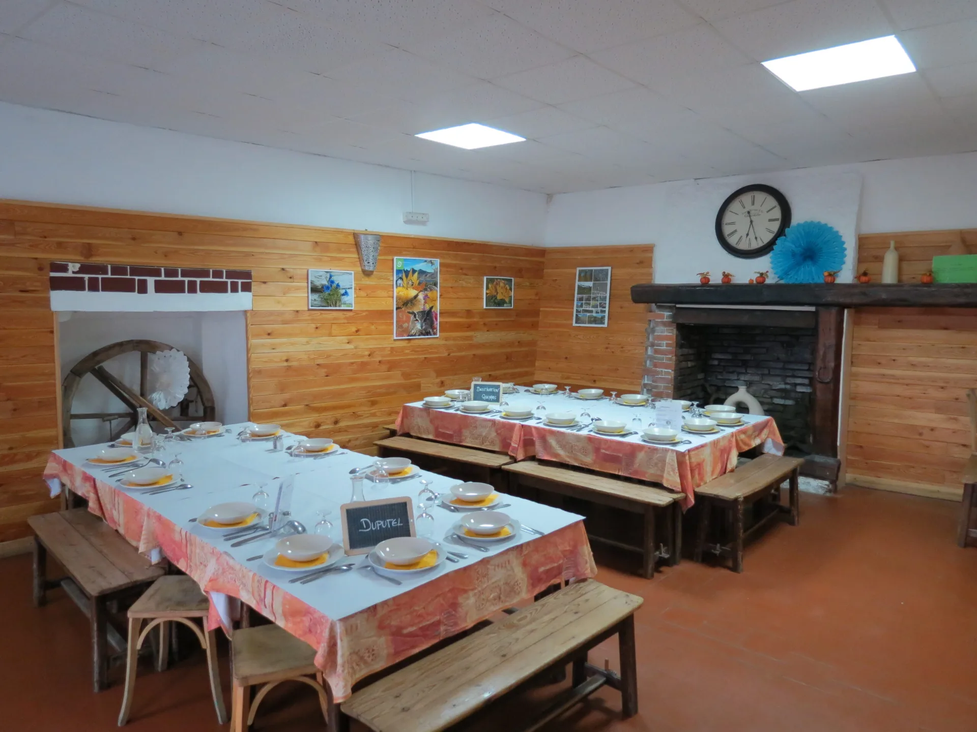 Salle a manger avec tables dressees pour trente convives murs en lambris et cheminee