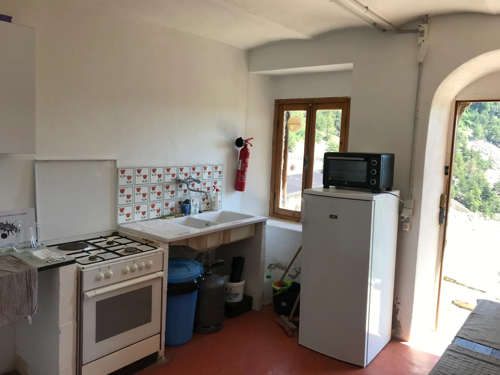 Cuisine equipee avec gaziniere evier et refrigerateur vue sur la montagne par la fenetre