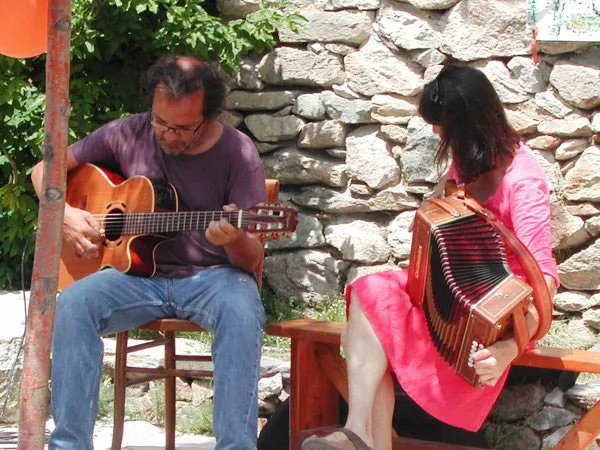 Animation musicale en terrasse avec guitariste et accordeoniste devant mur en pierres