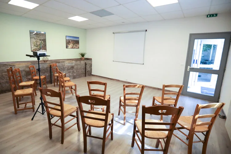 Salle de séminaire avec chaises disposées en arc de cercle et écran de projection