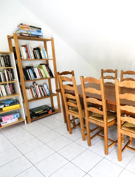 Salle de lecture avec bibliothèque garnie et grande table en bois pour les convives