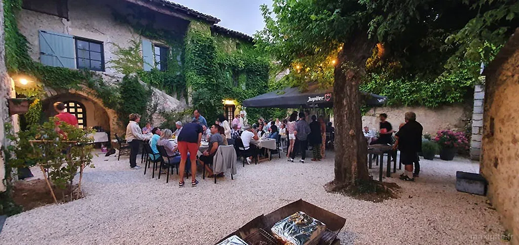 Dîner en soirée dans la cour avec convives attablés sous un barnum éclairé et façade illuminée
