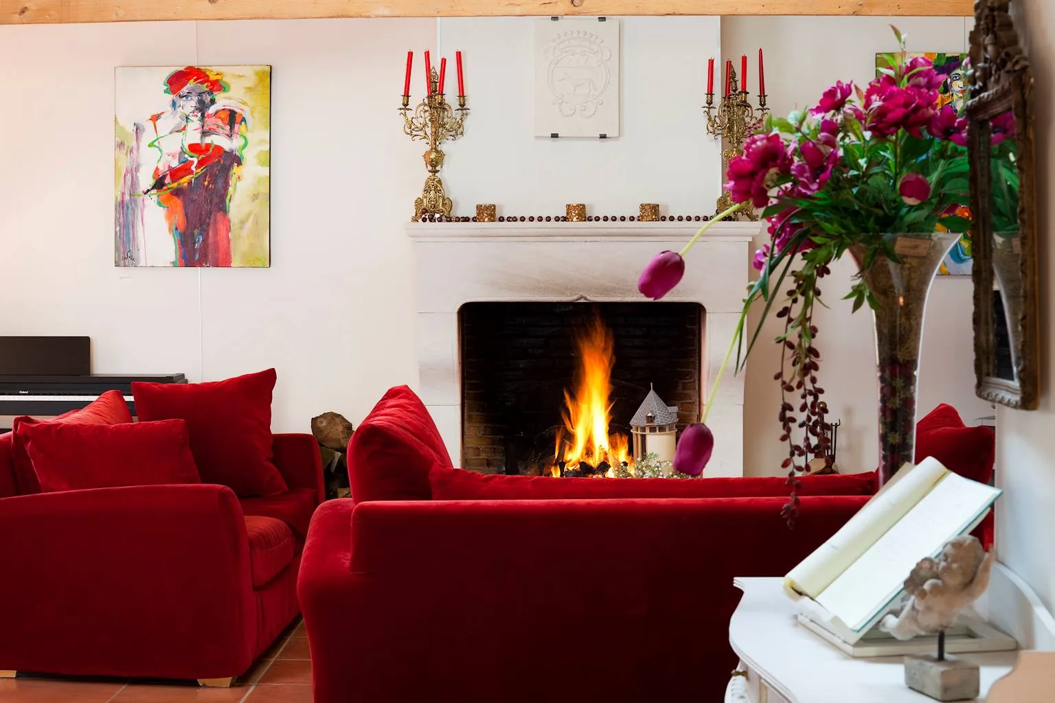 Grande salle à vivre lumineuse avec poutres apparentes en bois, table longue, tableaux colorés et plantes vertes