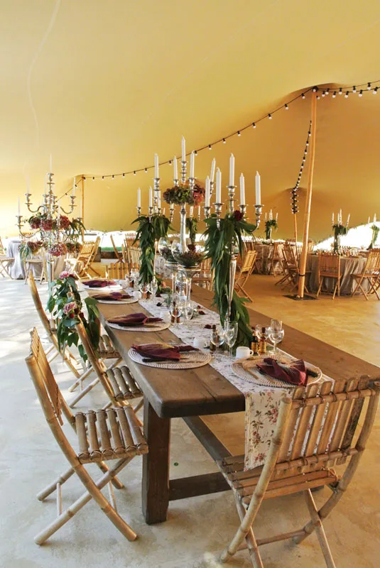 Grande table de réception dressée avec chandeliers, décorations florales et guirlandes lumineuses