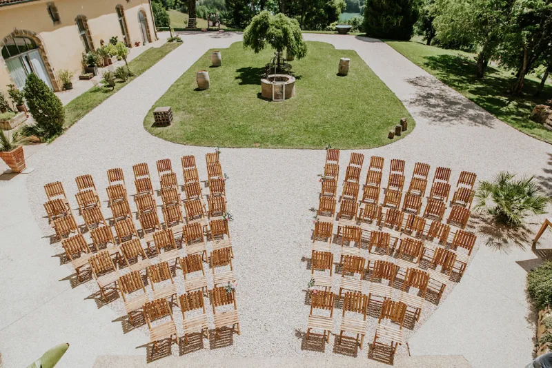 Vue aérienne de la cour d'honneur avec rangées de chaises en bambou disposées en arc sur la pelouse verte
