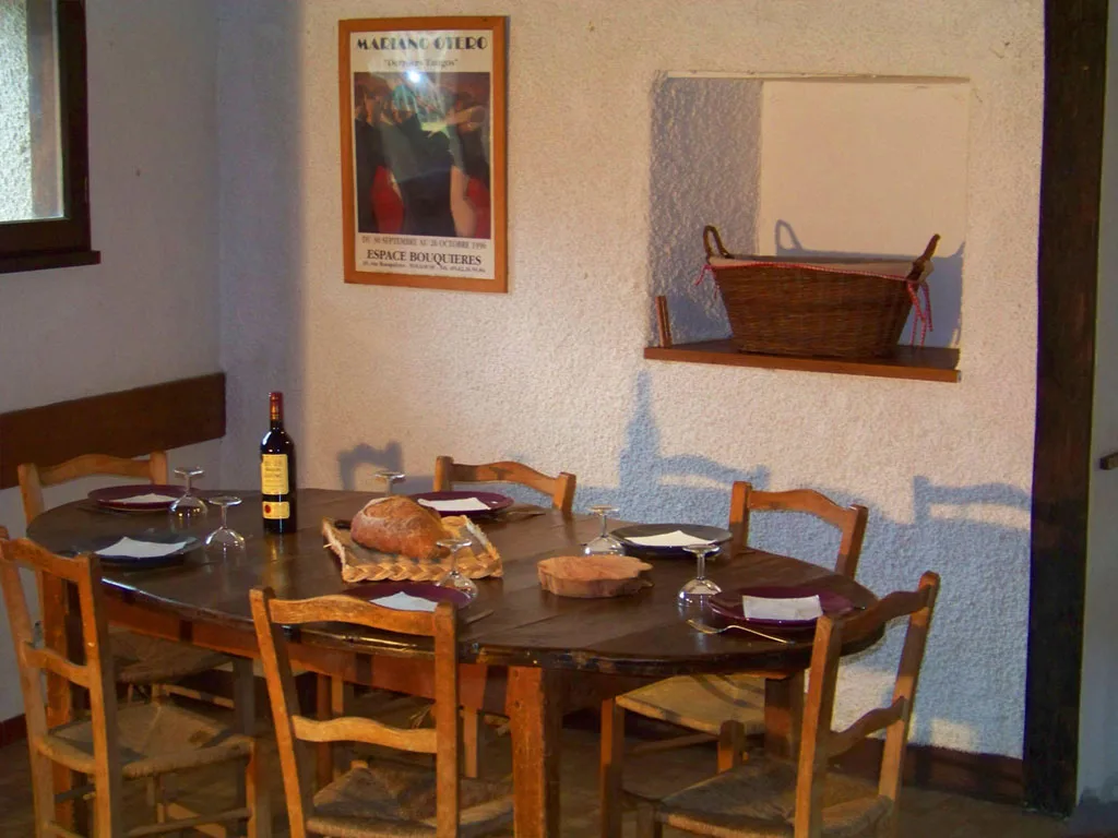 Coin repas intime avec table ronde en bois et chaises, murs bleu-gris décorés d'un tableau et d'un panier en osier