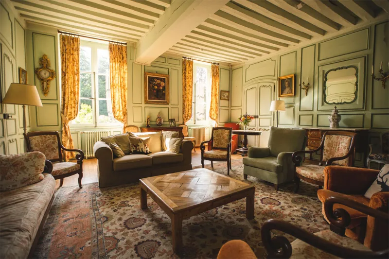 Grand salon du château avec cheminée en marbre, lustres et mobilier ancien de style classique