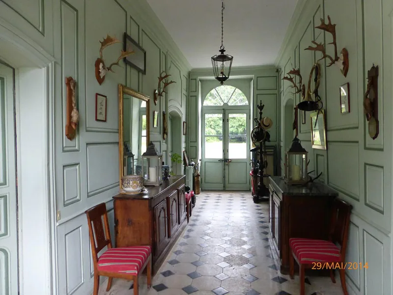 Façade principale du château en pierre avec sa tourelle et son entrée sous le porche